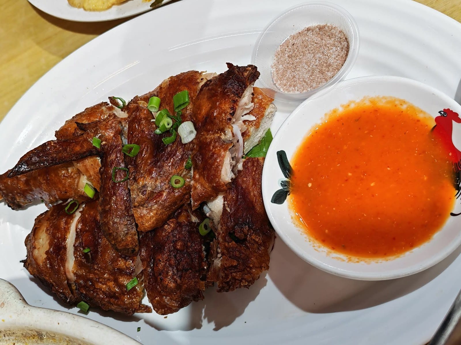 Crispy chicken cut into pieces, with a bowl of chilli dip and a pot of seasoning salt