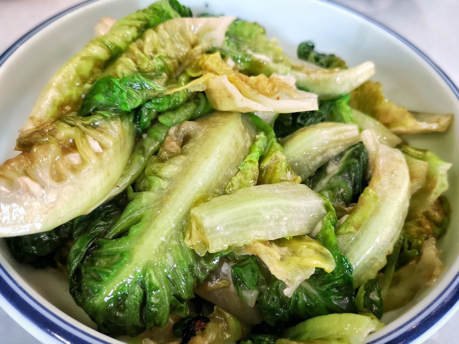 Stir-fried lettuce in a blue-rimmed bowl